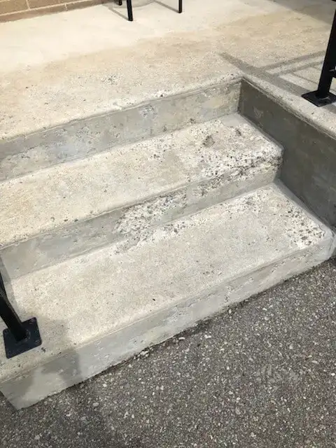Spalling concrete step with chipped surface and exposed aggregate