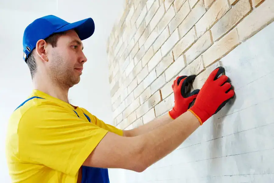 Installer placing thin brick veneer on a wall-mounted support system