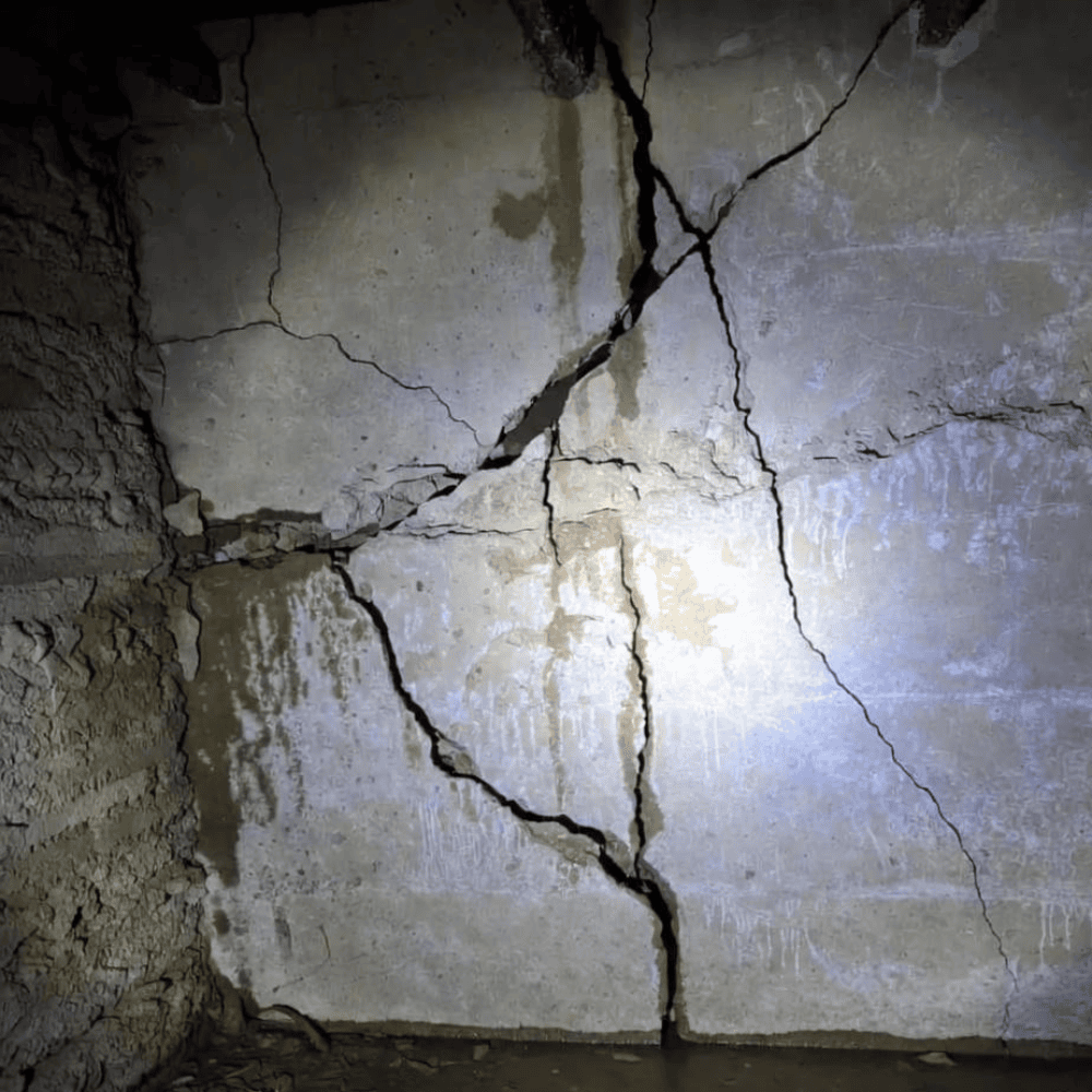 Severe intersecting cracks across a below-grade concrete foundation wall