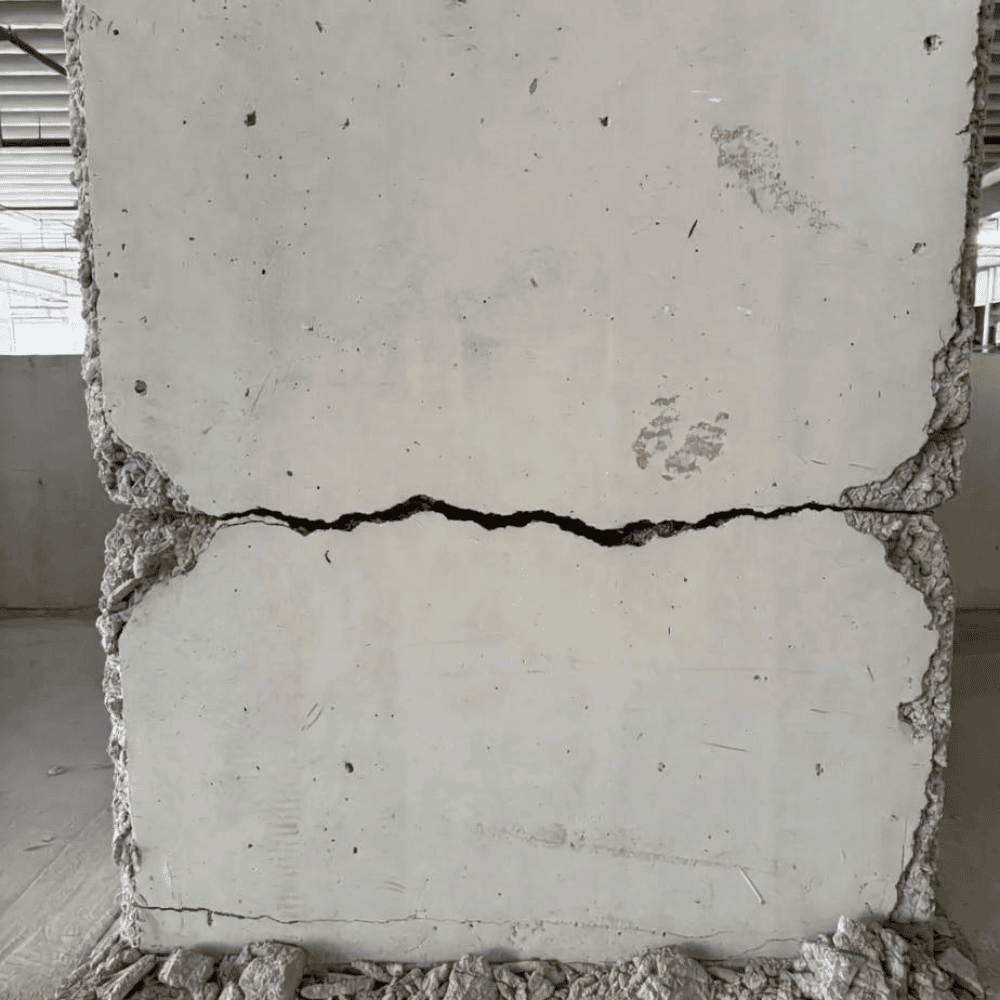Wide horizontal crack across a heavily damaged concrete structural column