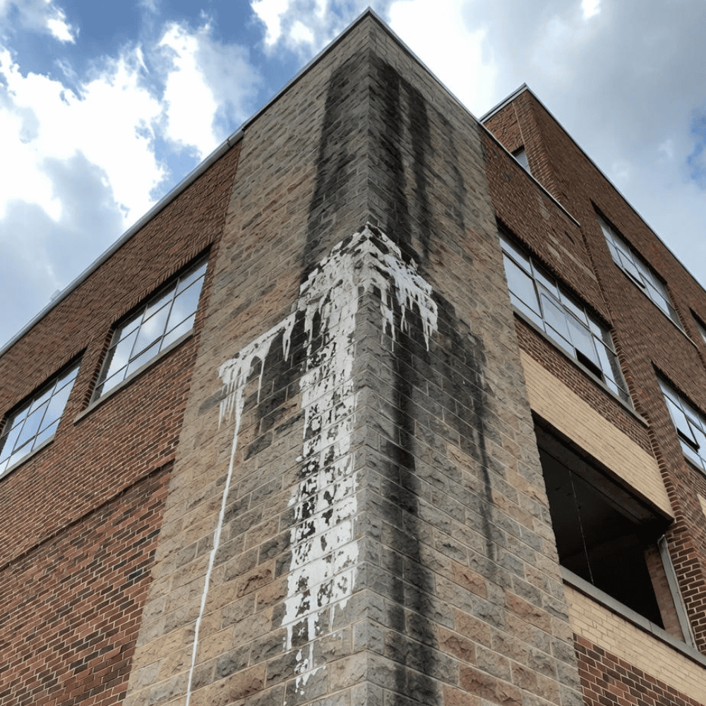 Commercial masonry corner with white mineral deposits and dark staining on gray concrete blockwork
