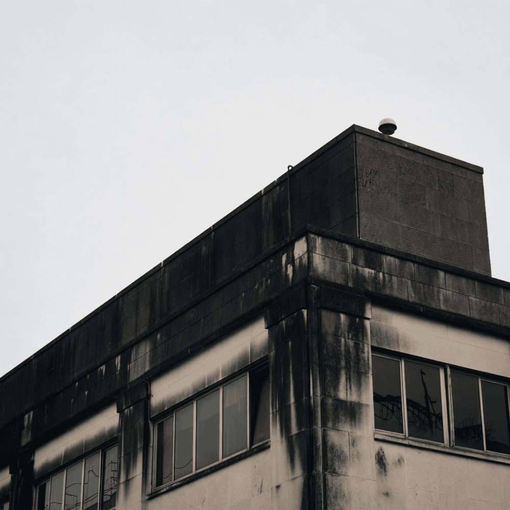 Commercial building facade with heavy soot staining and dark runoff streaks around upper walls and windows
