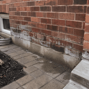 Lower masonry wall of a Toronto home with damp staining and recurring moisture signs