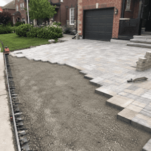 Interlocking stone driveway installation with compacted base and paver pattern