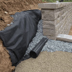 Drainage base preparation behind a retaining wall with gravel and pipe