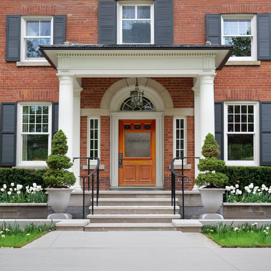 Beautiful brick house with white columns and lush landscaping.