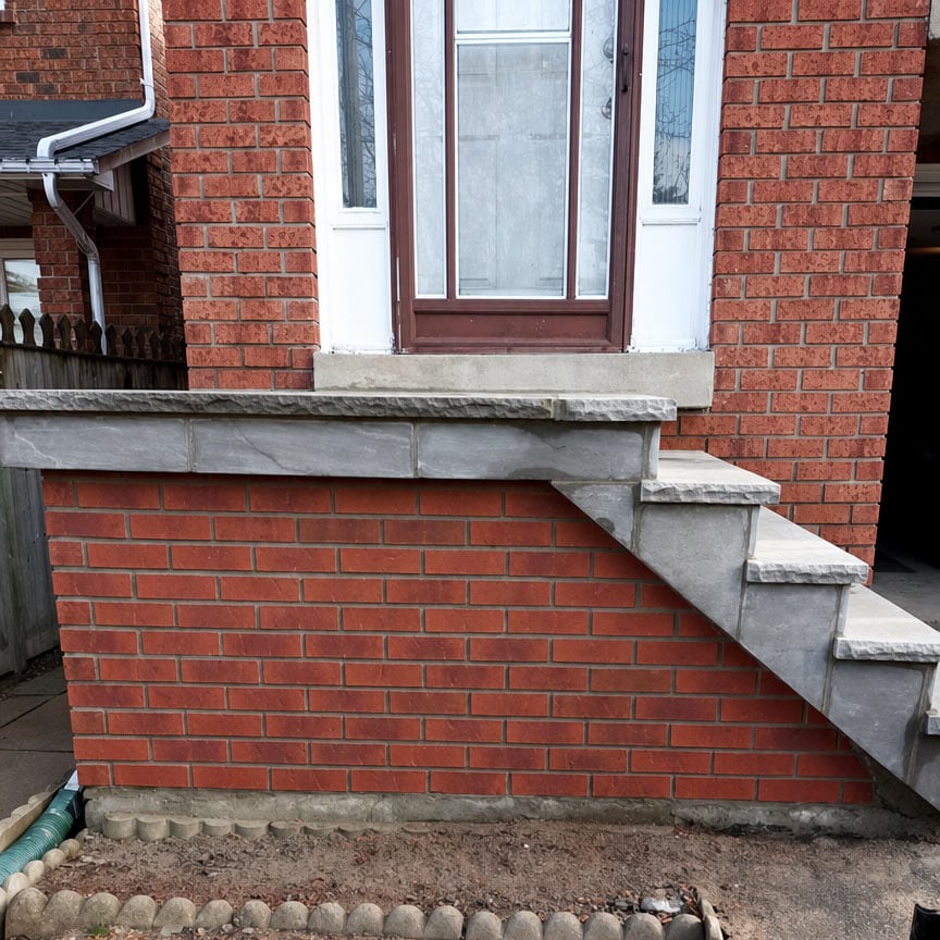 Brick and concrete stairs leading to a door with a glass panel.