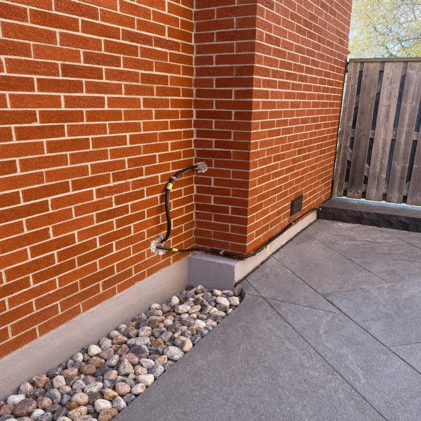 Close-up of brick wall and foundation with gravel and concrete.