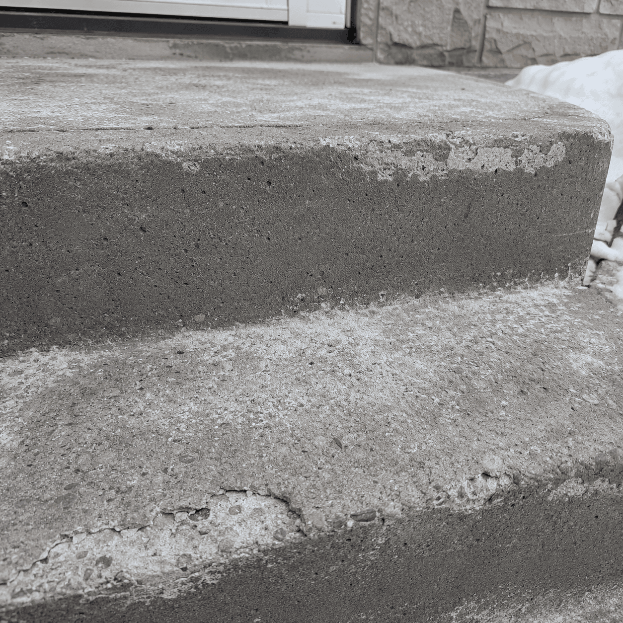 Weathered concrete steps with surface spalling.