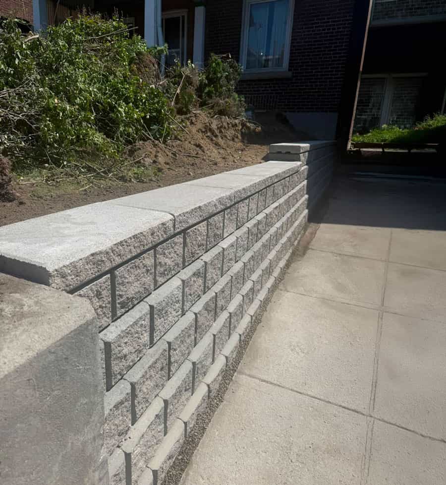 Concrete block retaining wall with a capped top beside a residential driveway