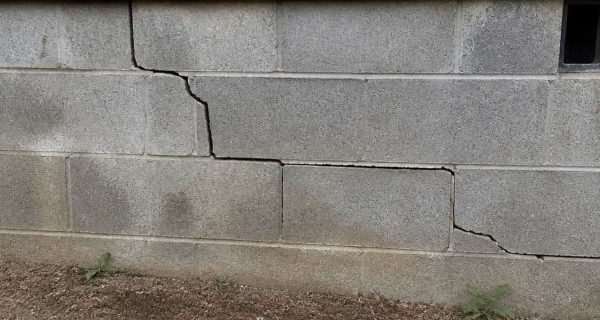 Large horizontal and stepped cracks across a concrete block wall