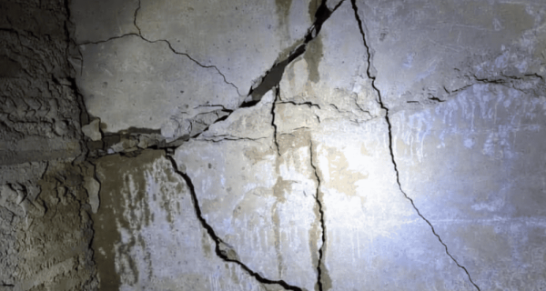 Severe intersecting cracks across a below-grade concrete foundation wall