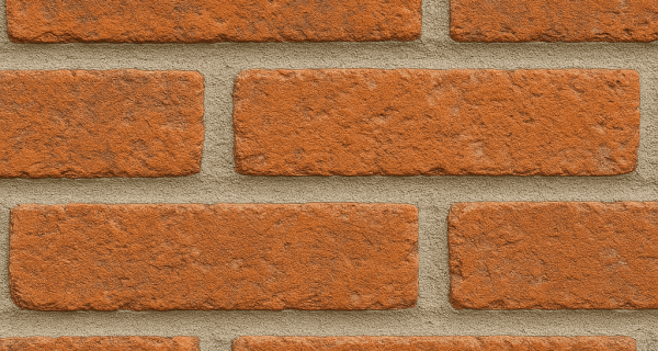 Close-up of orange brick wall with evenly filled light-gray mortar joints