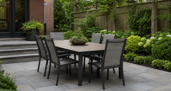 Landscaped stone patio with outdoor dining table beside a brick house