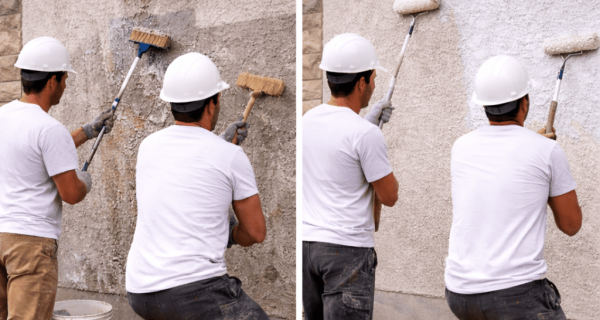 Workers brush and roll coating onto a textured stucco wall beneath a window