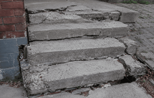 Badly damaged concrete steps with deep cracks and sinking sections