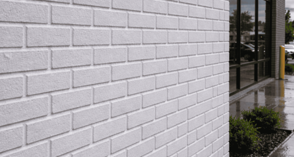 White-coated brick facade beside a glass storefront on a rainy day