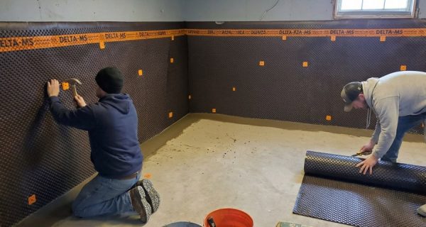 Workers install DELTA-MS dimpled membrane along basement walls and floor