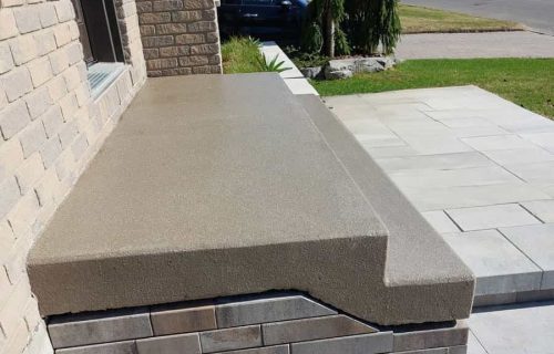 Concrete porch step beside a brick riser and paved front walkway