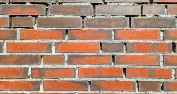 Close-up of red and brown brickwork with uneven, recessed mortar joints