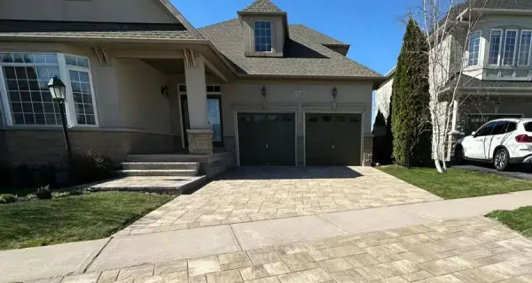 Interlocking stone driveway leading to a two-car garage and front entrance
